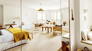 Ruime kamer met een groot bed, een slaapbank, twee fauteuils, een tafeltje en een hanglamp.
