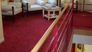 A room with a red carpet, white sofas, a small table, and a red railing. - Brit Hotel Nogent Le Rotrou Hotel Du Perche (Nogent-le-Rotrou)