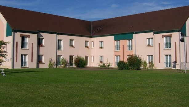 A multi-story building with a flat roof, multiple windows, and a central courtyard with grass and small plants. - Brit Hotel Nogent Le Rotrou Hotel Du Perche (Nogent-le-Rotrou)