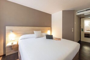 A hotel room with a large bed, bedside lamps, a laptop, and a door. - Hotel La Cle Des Champs (Claix)