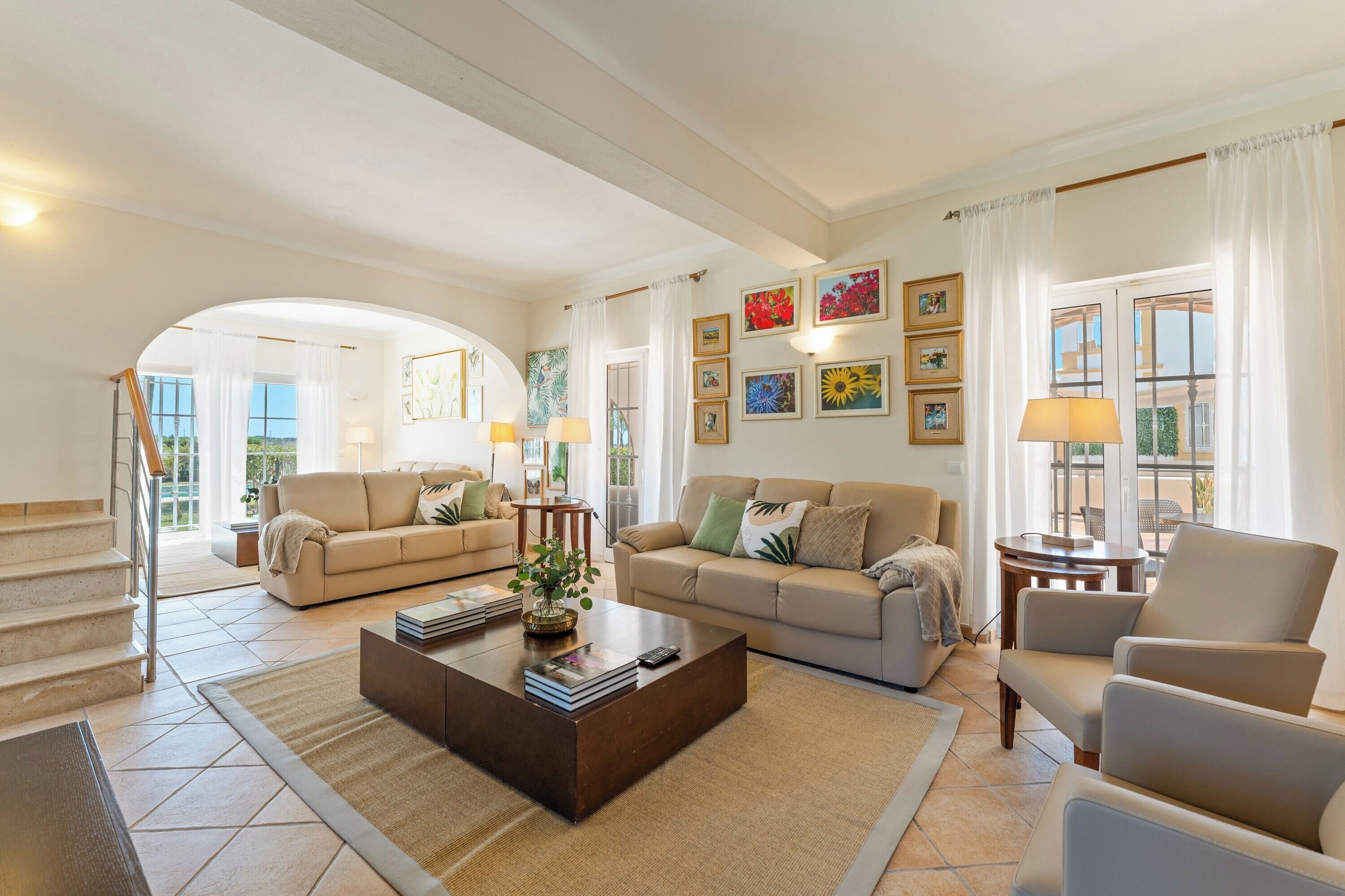 A spacious living room with a sofa set, a coffee table, and a staircase leading to an outdoor area.