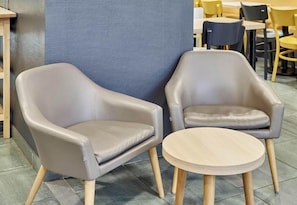 Due poltrone in pelle con gambe di legno e un piccolo tavolino in un caffè.