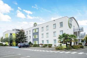 Un hotel moderno con facciata bianca, numerose finestre e un parcheggio.