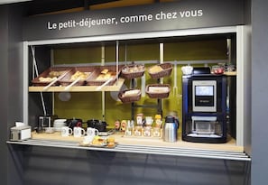 Un ricco buffet per la colazione con cestini di pane, dolci e una macchina per il caffè.