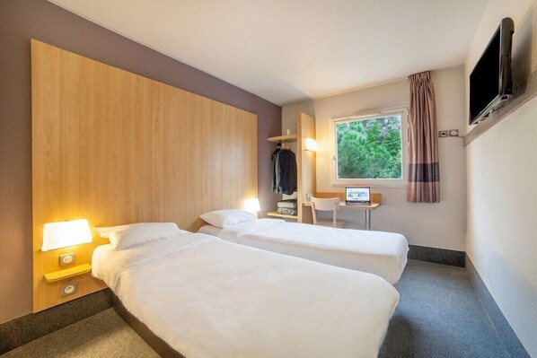 A hotel room with two beds, a TV, a desk with a computer, and a window with curtains. - B&B Hotel Evry Lisses 3 Etoiles (Lisses)