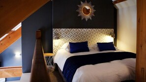 Un dormitorio con una cama, un espejo montado en la pared y un papel tapiz de diseño geométrico.