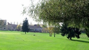 Un campo de golf con un club de campo y árboles.
