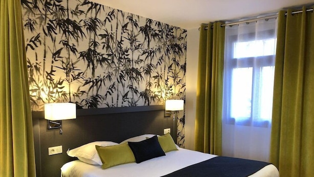 Habitación de hotel con una cama grande, cortinas verdes y un panel decorado con motivos de bambú.