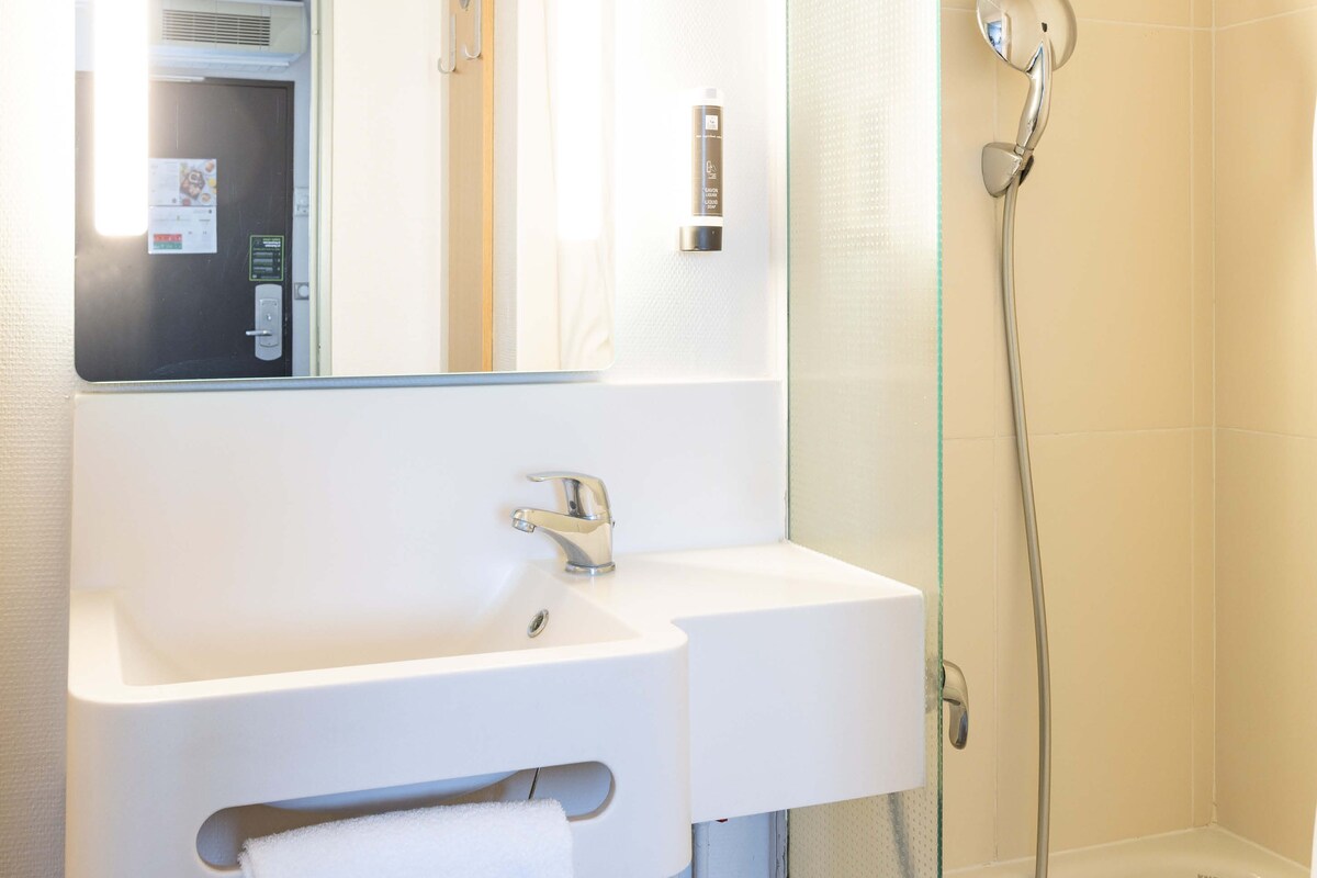 A modern bathroom with a white sink, mirror, and shower.