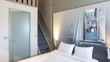 A hotel room with a bed, a staircase, and a mural of a street scene.