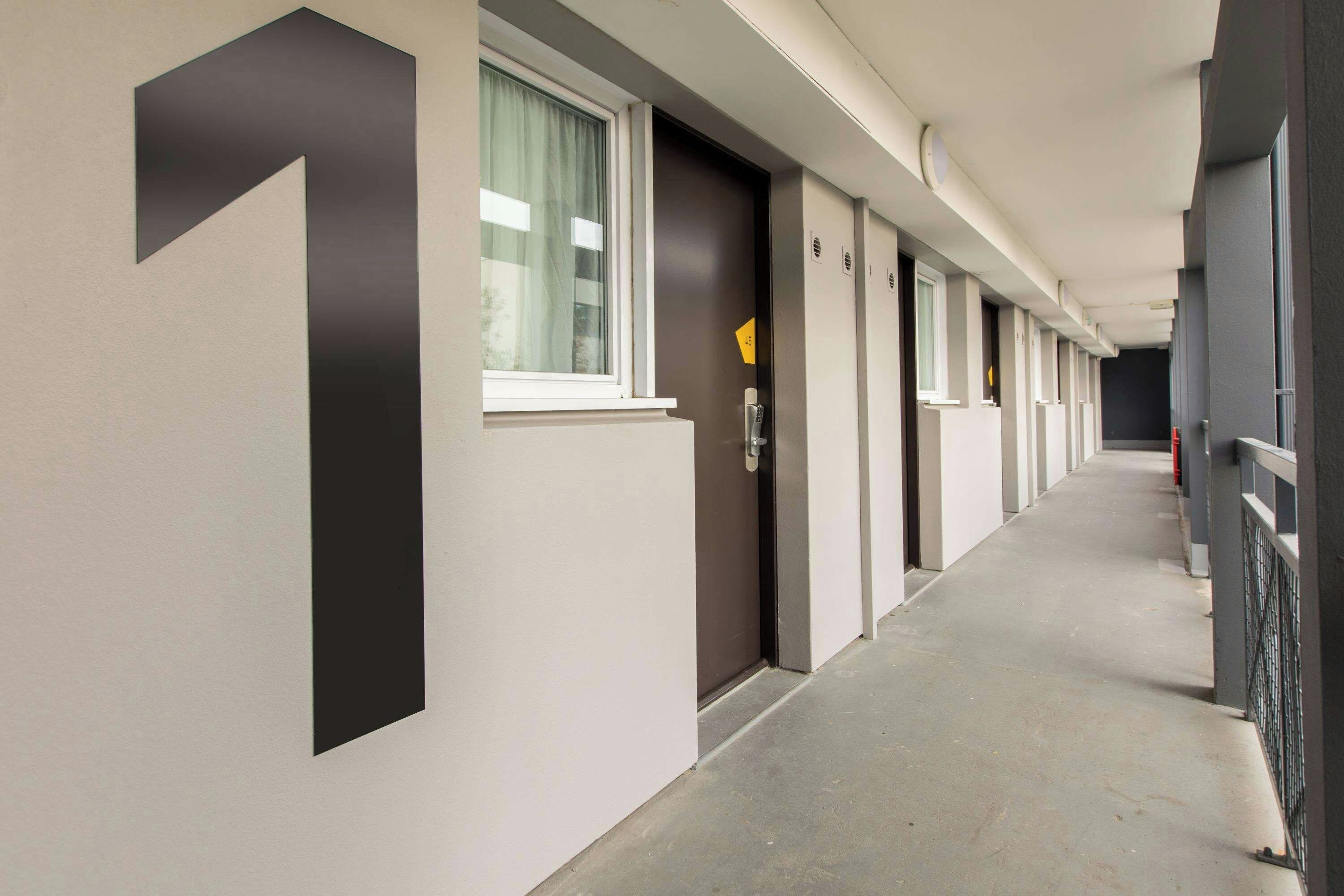 A corridor with doors numbered 1 to 6, a window with curtains, and a door with a lock.
