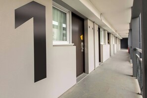 A corridor with doors numbered 1 to 6, a window with curtains, and a door with a lock. - B&B Hotel Rennes Nord St Gregoire (Saint-Gregoire)
