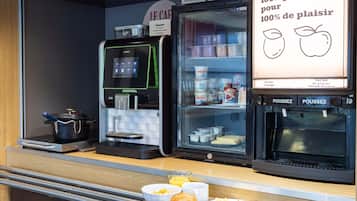 A breakfast counter with a coffee machine, a refrigerator with dairy products, and a sign advertising 100% pure juice.