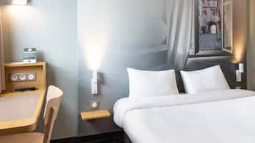 Hotellihuoneessa on sänky, työpöytä ja tuoli. Ikkunasta avautuu näkymä kadulle.
