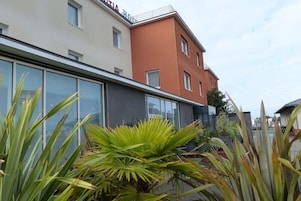 Un hotel moderno con techo plano, ventanas amplias y paredes exteriores en tonos blanco y naranja.