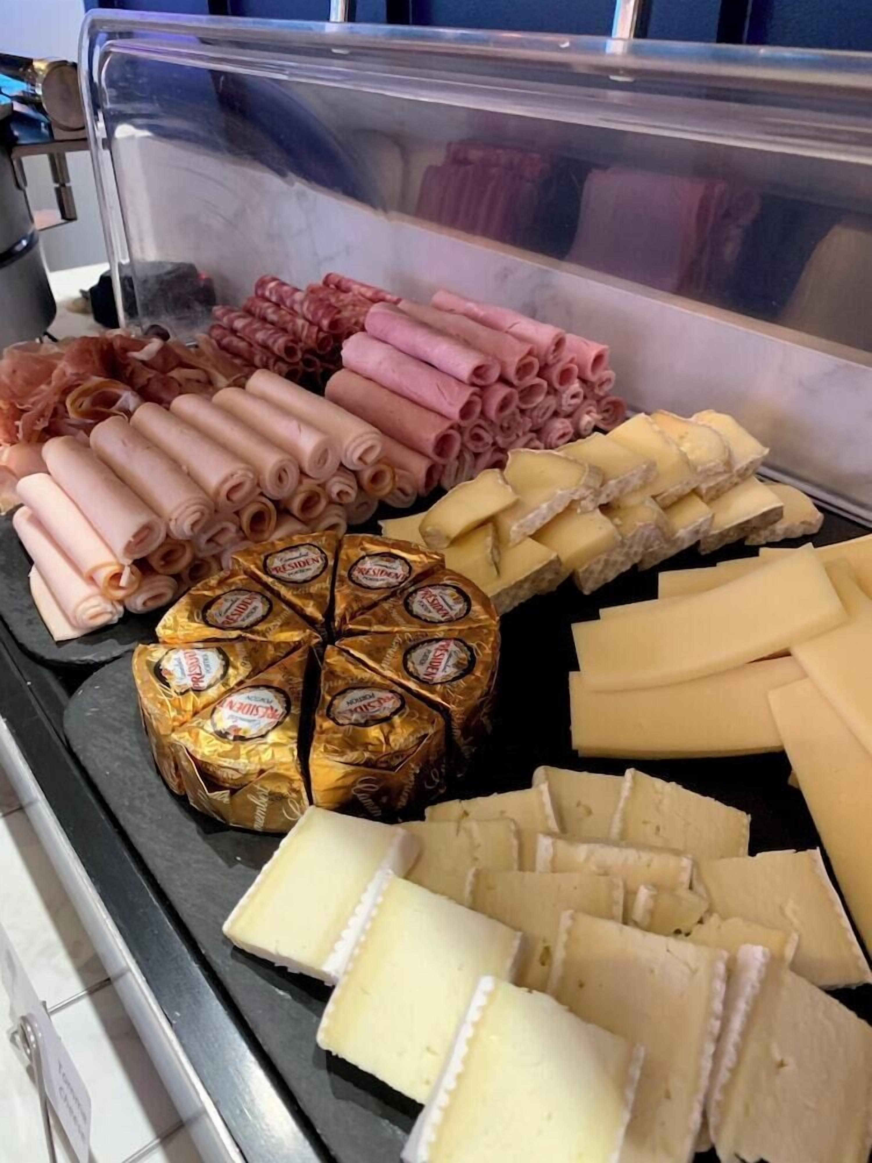 Exposição de queijos e enchidos com diversos tipos de queijos e carnes curadas.
