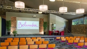 A conference room with a stage, a large screen displaying 'Belambra business,' rows of chairs, and a staircase. - Club Belambra Le Normont (Dourdan)