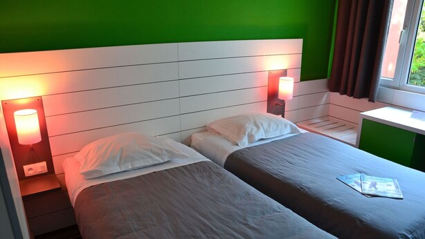 A double bed with two pillows, a bedside table, and a lamp. - Club Belambra Le Normont (Dourdan)