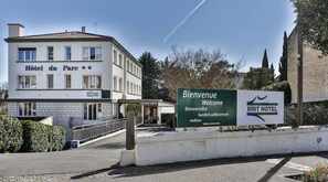 En hotelindgang med et skilt, der viser "Bienvenue Welcome Bienvenidos Willkommen" og "BRIT HOTEL" på flere sprog.