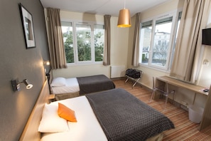 Een hotelkamer met twee bedden, een bureau, een stoel, een radiator en een televisie.