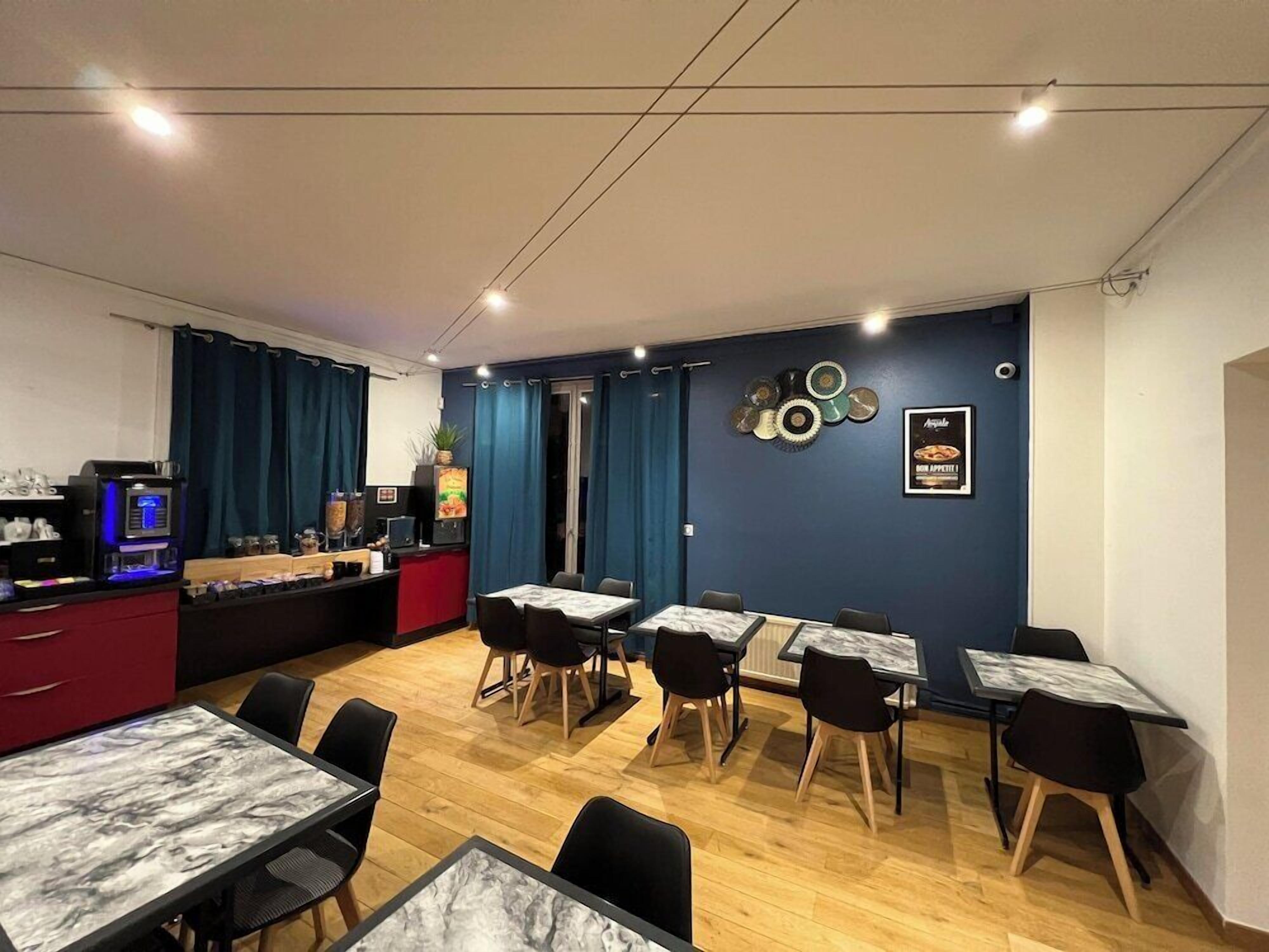 Un espace repas avec des tables et des chaises, une machine à café et un comptoir où est affiché le menu.