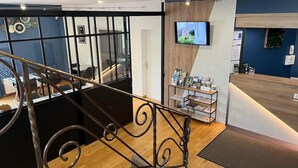 Een modern interieur met een houten trap, een receptiebalie en een televisiescherm.
