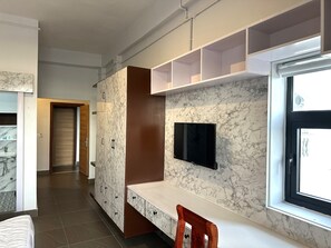 Un intérieur moderne avec un mur en marbre, un téléviseur à écran plat, un banc en bois et une fenêtre.