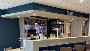Un espace bar avec un comptoir, des tabourets et des étagères remplies de bouteilles.