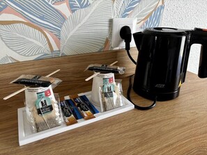 A coffee maker, a tray with sugar packets, and a spoon holder on a wooden table. - Brit Hotel Saint Lo Hotel Lunotel (Saint-Lo)