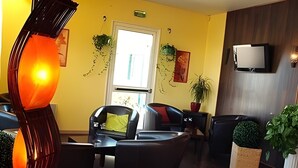 A hotel lobby with a modern design, featuring a large orange sculpture, multiple seating areas, and potted plants. - Hotel Des Portes De Meuse (Pagny-sur-Meuse)