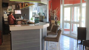 A modern bar area with a counter, seating, and a large window. - Hotel Des Portes De Meuse (Pagny-sur-Meuse)