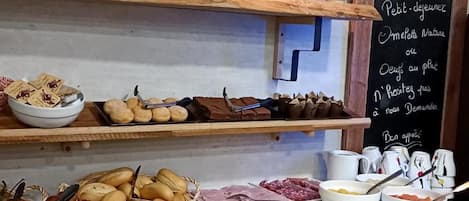Un bufé de desayuno con diversas opciones de comida y un menú en pizarra.