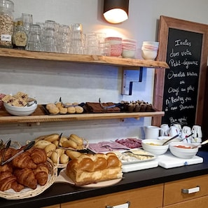 A breakfast buffet with various food items and a chalkboard menu. - Hotel Des Portes De Meuse (Pagny-sur-Meuse)