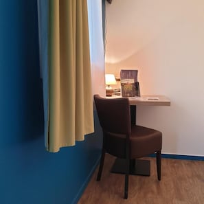 A room with a desk, chair, and a lamp. There are books on the desk. - Hotel Des Portes De Meuse (Pagny-sur-Meuse)