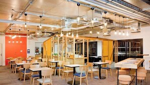A modern dining area with multiple tables and chairs, exposed ductwork, and hanging pendant lights. - Ibis Styles Chlons-en-champagne Centre (Chalons-en-Champagne)