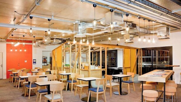 A modern dining area with multiple tables and chairs, exposed ductwork, and hanging pendant lights. - Ibis Styles Chlons-en-champagne Centre (Chalons-en-Champagne)