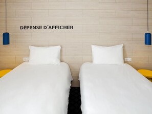 A hotel room with two beds, a wooden headboard, and two blue wall-mounted lamps. - Ibis Styles Chlons-en-champagne Centre (Chalons-en-Champagne)