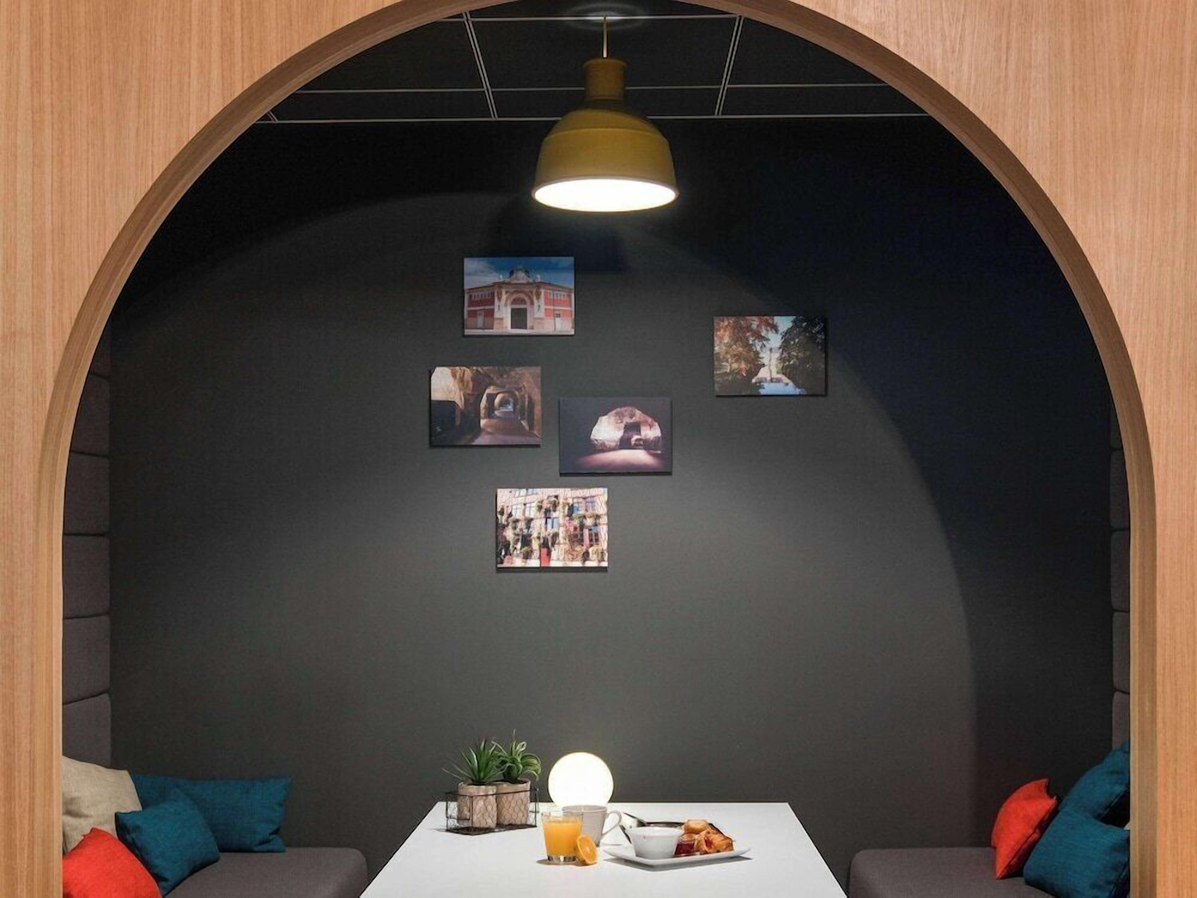 Una habitación acogedora con un arco de madera, una mesa con desayuno y cuadros en la pared.