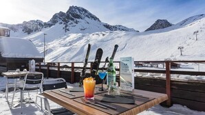 A snow-covered mountain view with a wooden table, chairs, skis, and a sign. - Hotel Tignes Le Diva (Tignes)