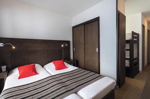 A hotel room with a bed, a wardrobe, a nightstand, and a lamp.
