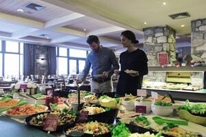 A buffet with various food items and a stone pillar in the background.