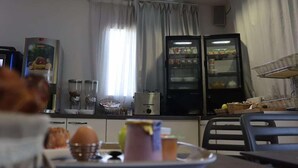 A kitchen with a refrigerator, microwave, and a window with curtains. There are various kitchen items on the counter. - Village Hotel (Villefontaine)