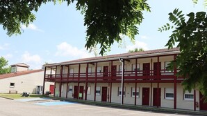 A motel with a two-story structure, a parking lot, and a swimming pool. - Village Hotel (Villefontaine)
