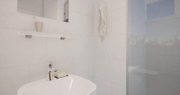 A modern bathroom with a white sink, a mirror, and a shower area. - Citotel Leopol (Lorient)