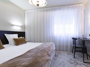 A hotel room with a large bed, a desk, and a chair. - Citotel Leopol (Lorient)