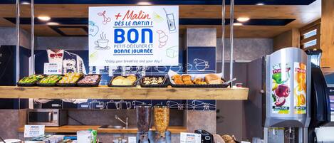 Un bufé de desayuno con diversas opciones de alimentos, una máquina de café y un cartel que promociona un desayuno saludable.