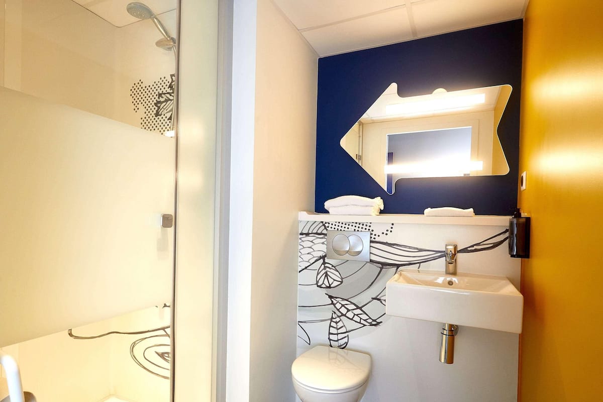 A bathroom with a shower, toilet, sink, and a mirror.