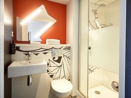 A bathroom with a white sink, a toilet, a mirror, and a shower.