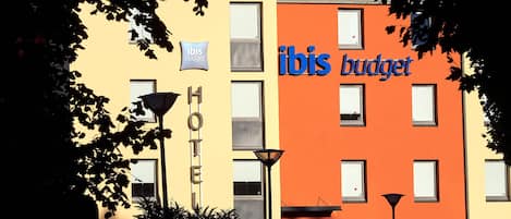 A hotel with 'ibis budget' signage, a 'HOTEL' sign, and a 'RUSIA' sign indicating a Russian location.
