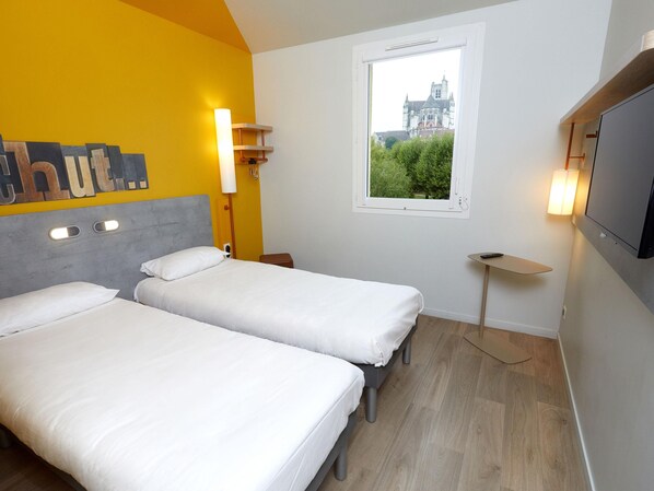 A hotel room with two beds, a window with a view of a building, a TV, and a small table. - Ibis Budget Auxerre Centre (Auxerre)